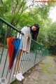 A woman standing on a bridge holding an umbrella.