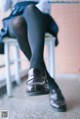 A woman sitting on a chair wearing black tights and a skirt.