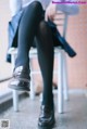 A woman sitting on a chair wearing black tights and shoes.