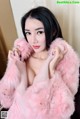 A woman in a pink fur coat posing for the camera.