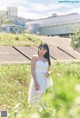 A woman in a white dress standing in a field.