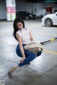 A woman sitting on the ground in a parking garage.