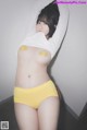 A woman in a white shirt and yellow panties posing for the camera.