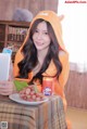 A woman in a bear costume sitting at a table with a plate of grapes.